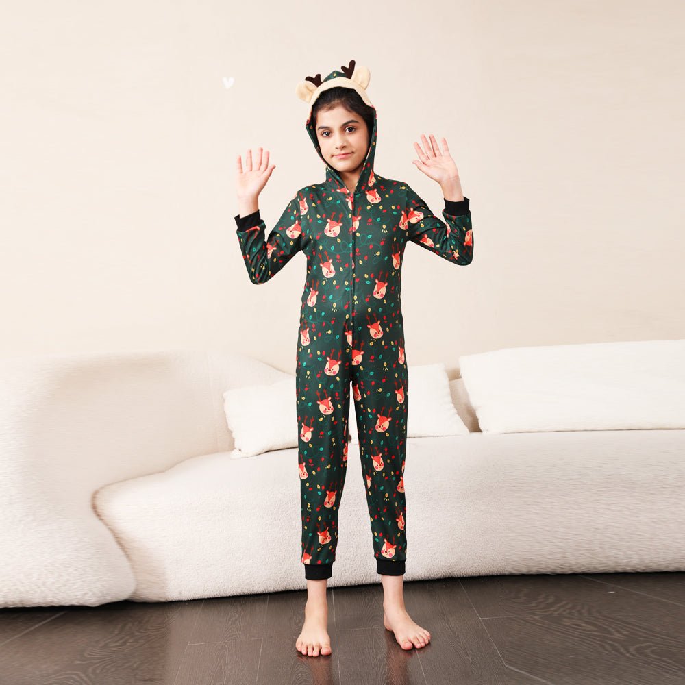 Child raising both hands in a green Christmas print onesie with a reindeer face hood, antlers and black cuffs.