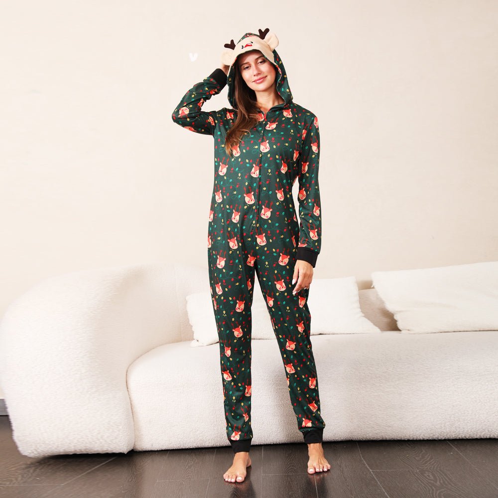 Front view of a woman in a green Christmas print zip-up onesie with a reindeer face hood, antlers and black cuffs.