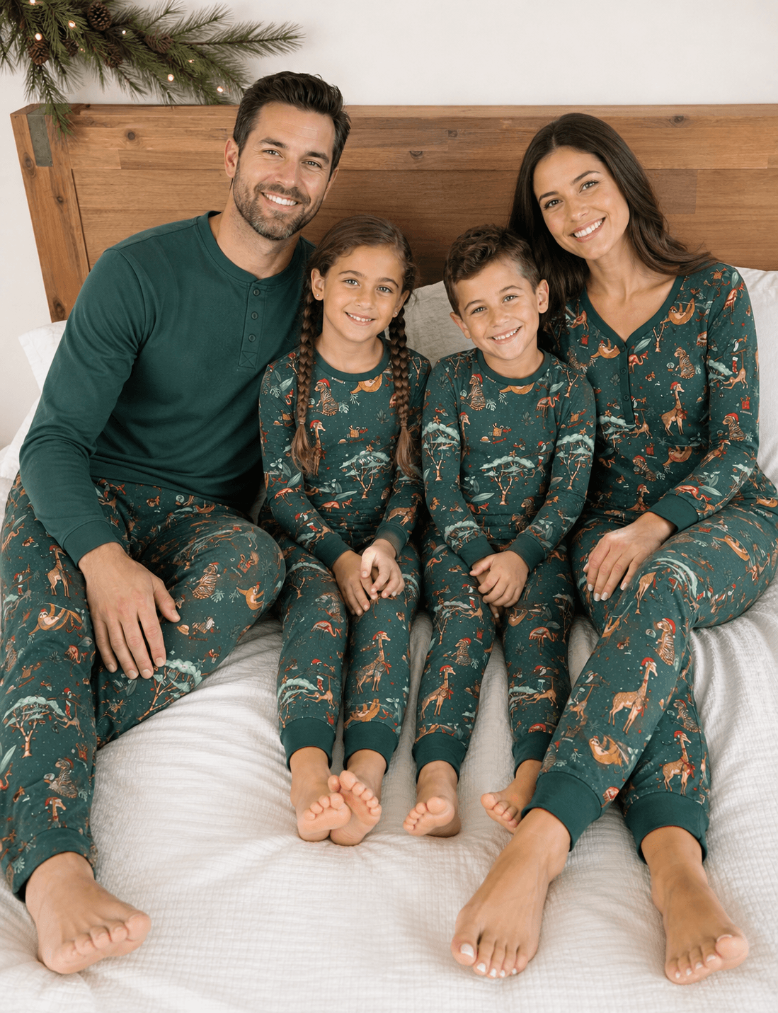 Genitori e due bambini che sorridono su un letto in pigiami verdi con animali; il padre indossa una maglia verde in tinta unita.