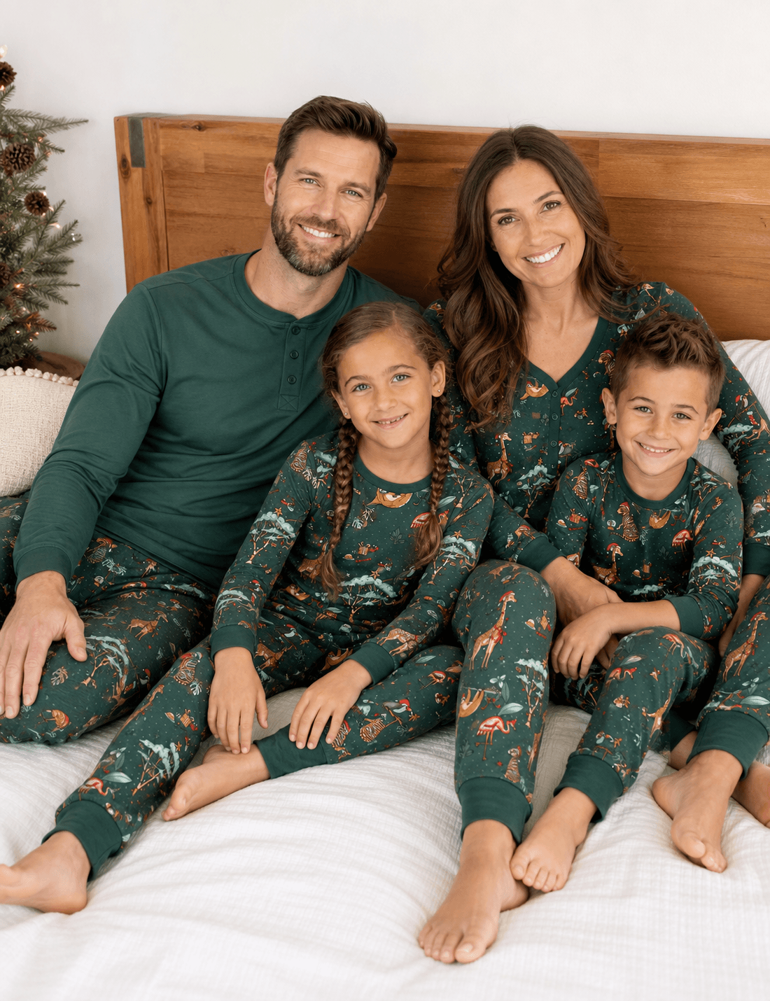 Parents and two children on a bed in green animal print pajamas; the father's set has a solid green Henley top.