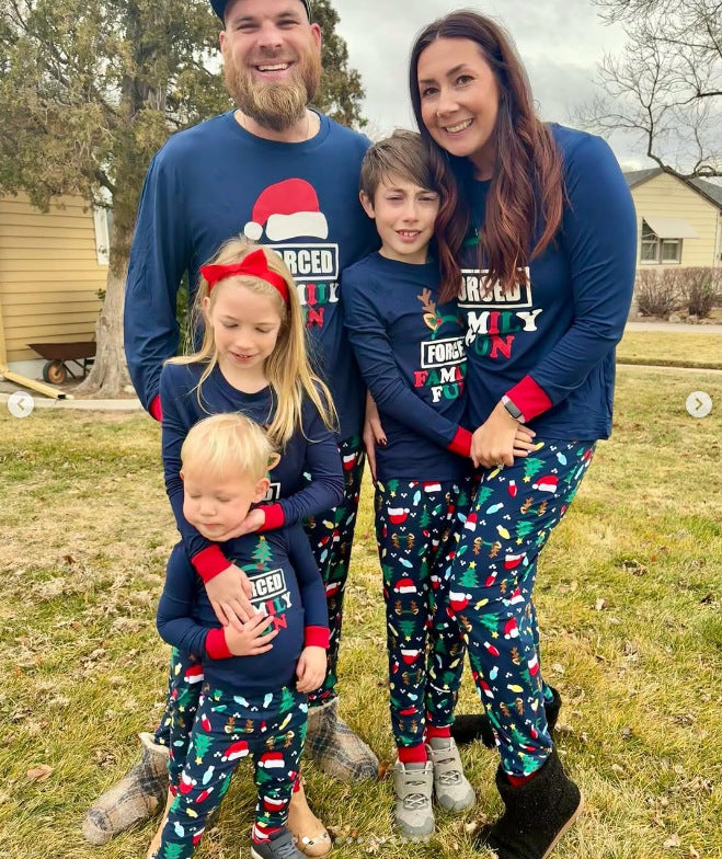 Outdoor family portrait in navy Forced Family Fun Christmas pajama tops with red cuffs and colorful printed pants.