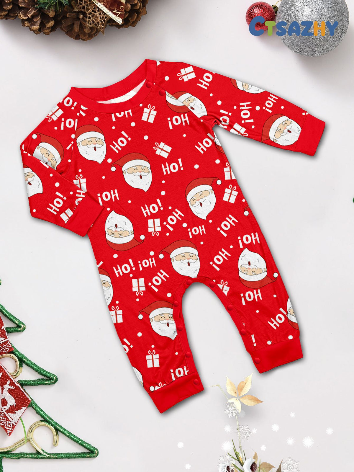 Flat lay of a red baby Christmas romper with Santa faces, gifts and Ho lettering, long sleeves and shoulder snaps.
