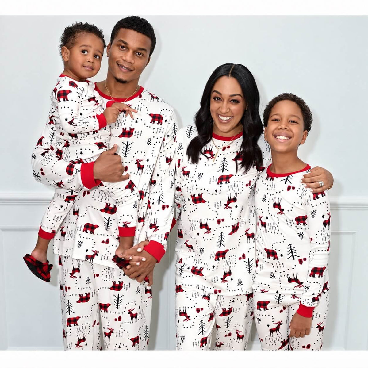 Parents and two children wearing white woodland-print pajama sets with red necklines and cuffs.