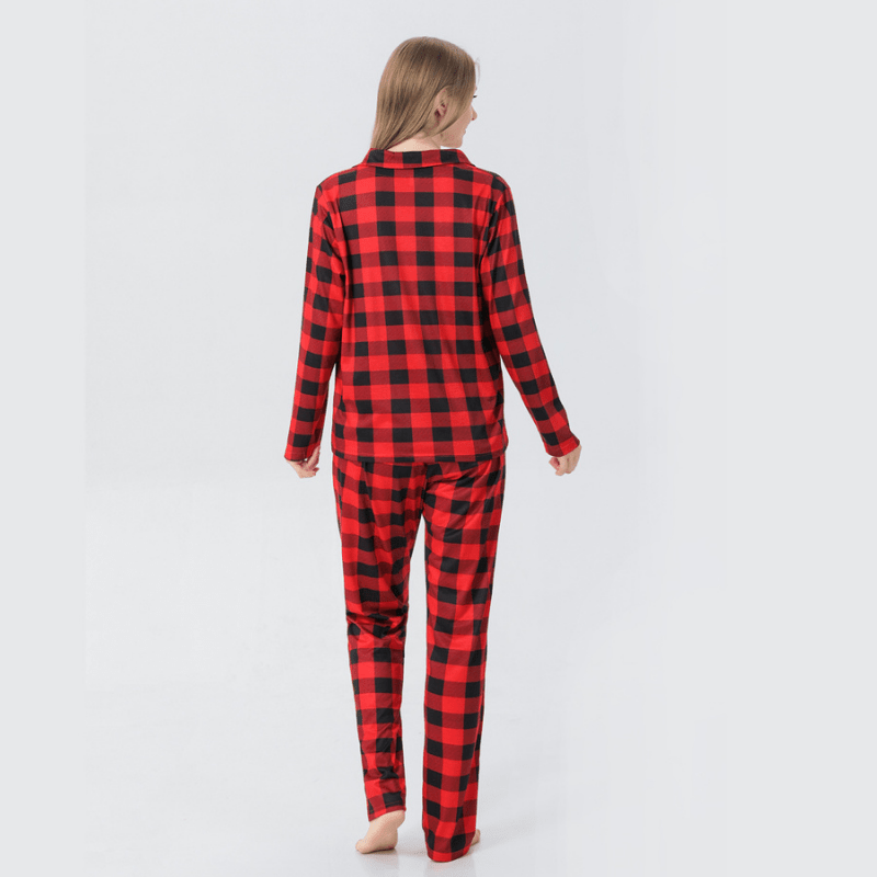 Rear view of a woman in red and black buffalo plaid button-front pajamas against a white background.