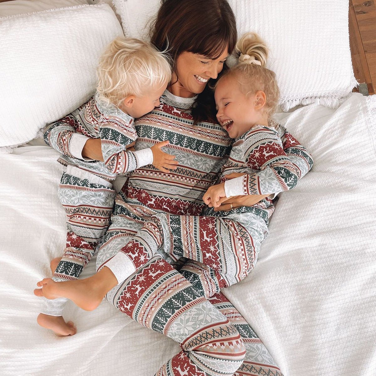 Mom Snuggling Two Giggling Toddlers on White Bed in Fair Isle Christmas Pajamas – Aerial View Showing Full Pajama Pattern Detail