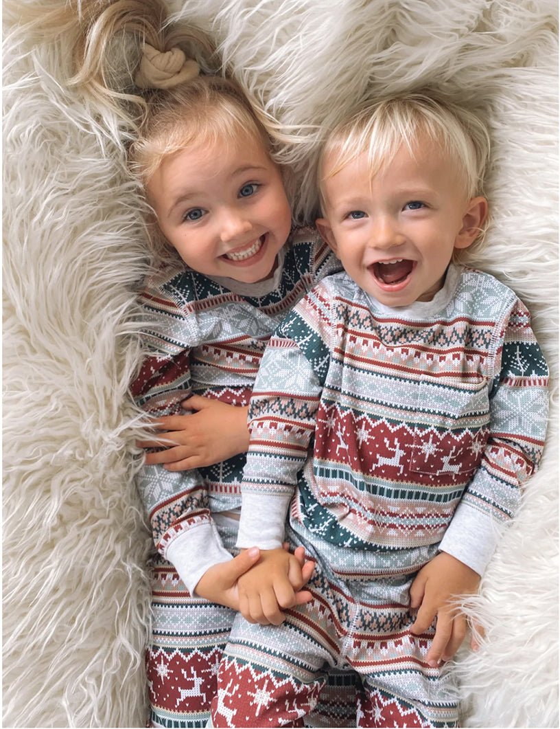 Two Laughing Toddlers Lying Side by Side on Fluffy White Rug in Matching Fair Isle Christmas Pajamas – Overhead Close-Up of Girl and Boy Smiling at Each Other