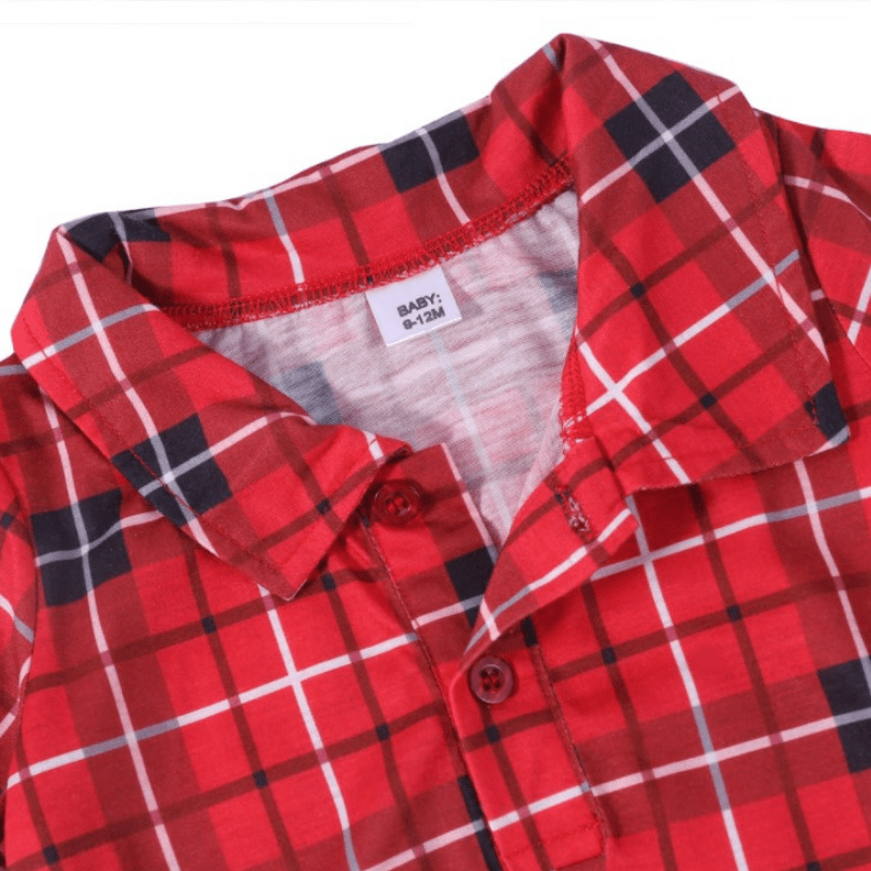 Nahaufnahme des Kragens, der vorderen Knöpfe und des Baby-Größenetiketts an einem rot-schwarz-weißen Tartan-Weihnachtsstrampler.
