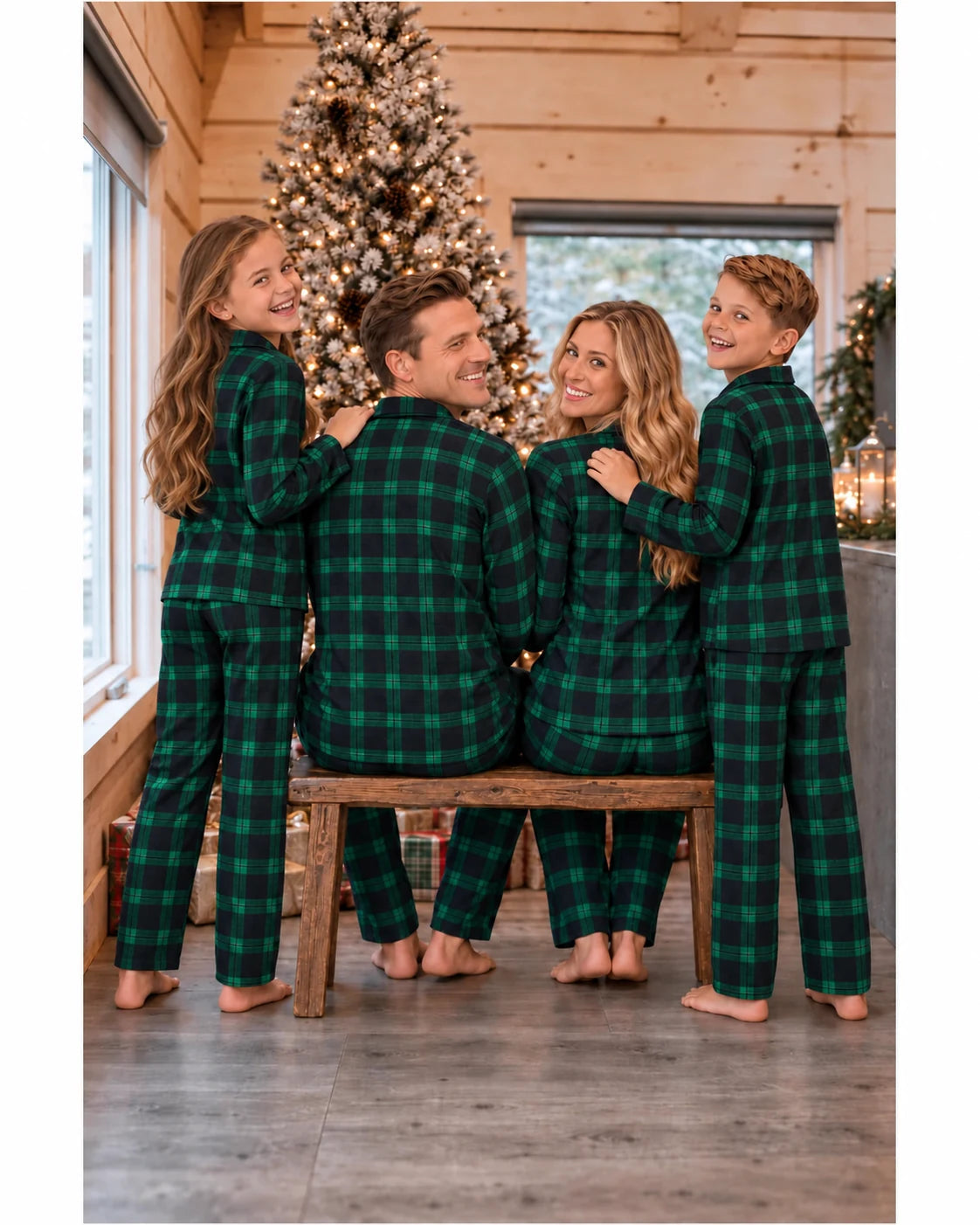 Back view of a family wearing green and black plaid pajamas beside a Christmas tree in a cabin.