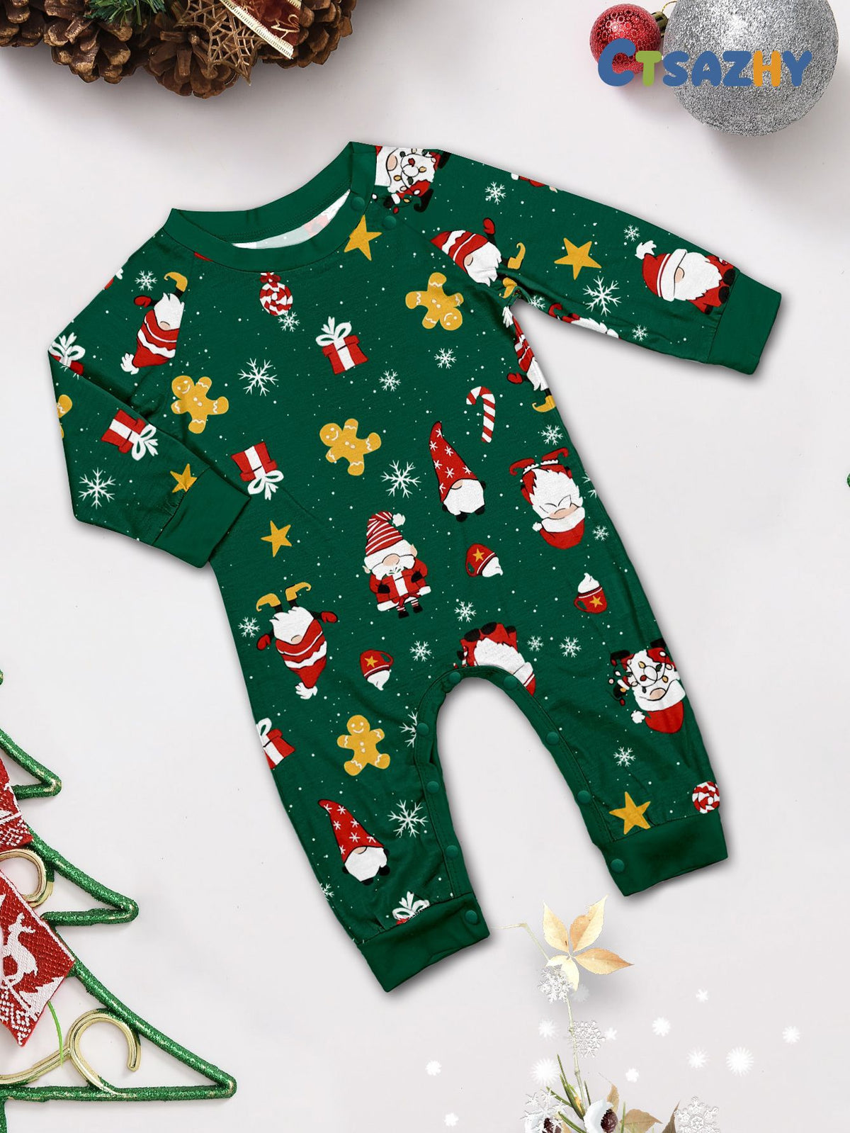 Tutina natalizia verde per neonato con Babbo Natale, pan di zenzero, stelle e regali e bottoni automatici sulle spalle, disposta in piano.