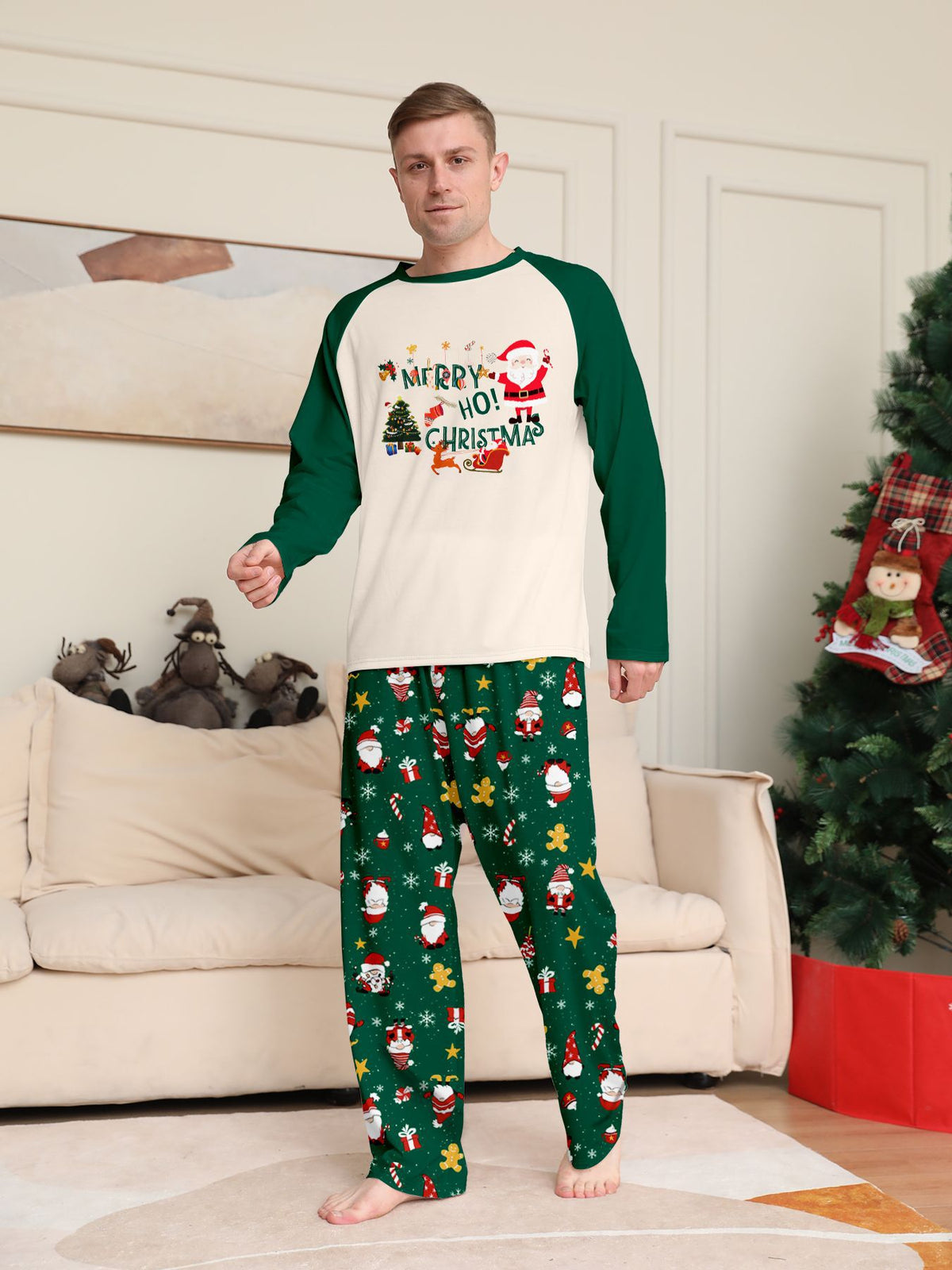 Vista frontale di un uomo con maglia color crema del pigiama con motivo natalizio e maniche verdi e pantaloni verdi con Babbo Natale.