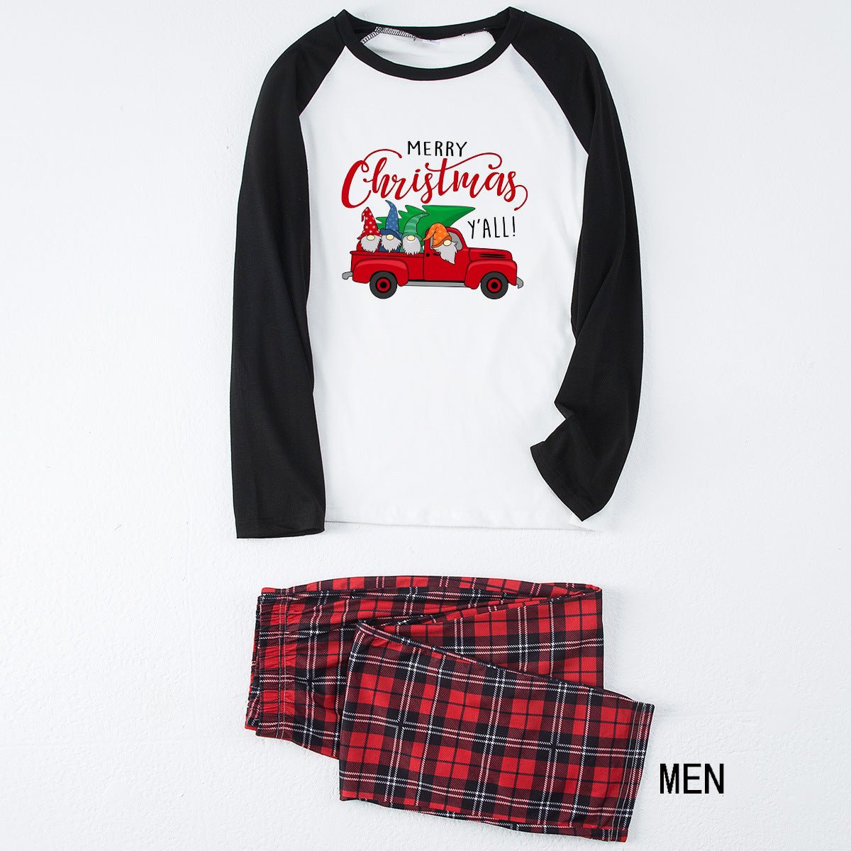 Pigiama da uomo disposto in piano, con maglia bianca Merry Christmas Y'all con camion, maniche raglan nere e pantaloni in tartan rosso.