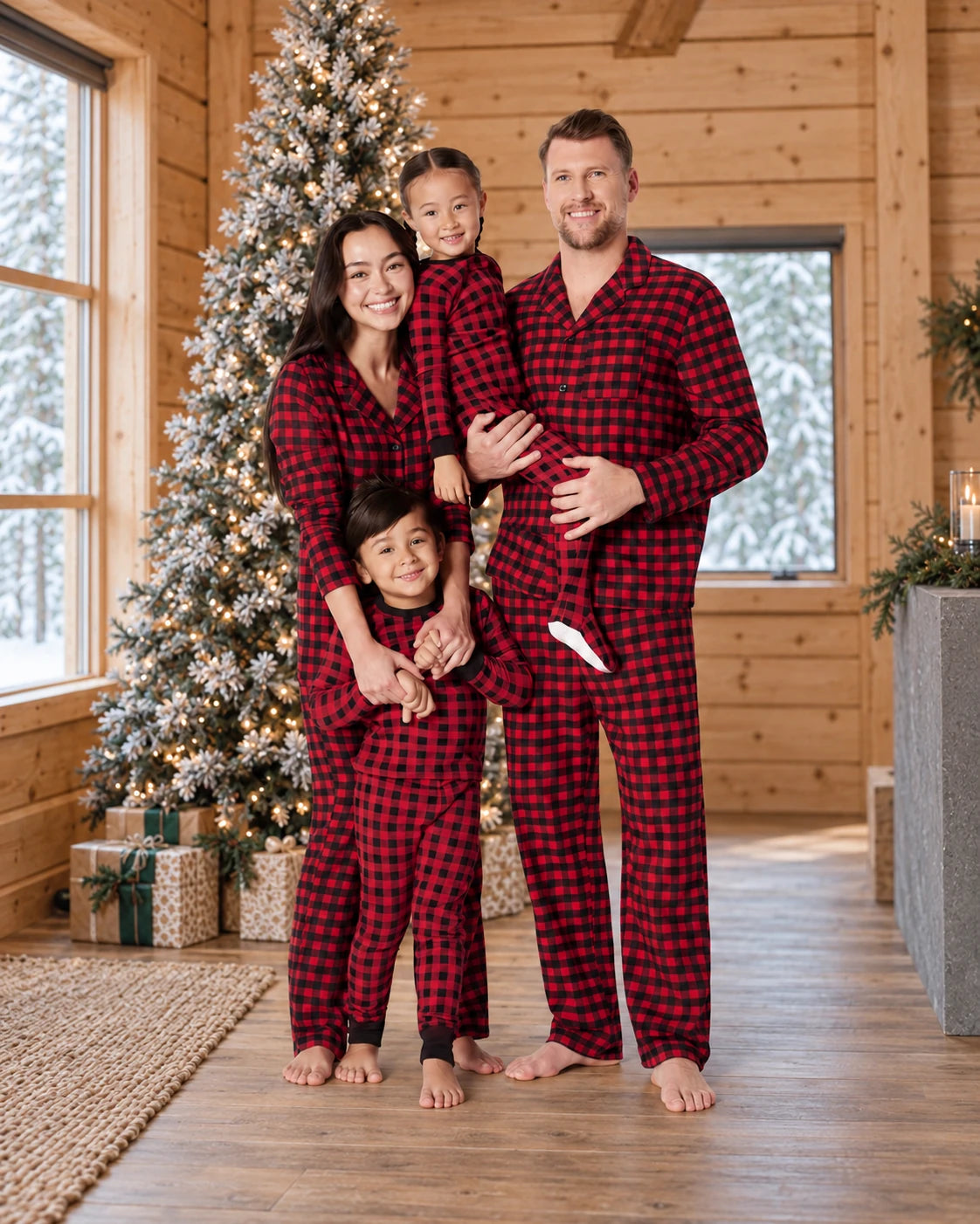 Family in red and black check pajama sets beside a Christmas tree in a wood-paneled room.