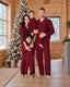 Family in red and black check pajama sets beside a Christmas tree in a wood-paneled room.