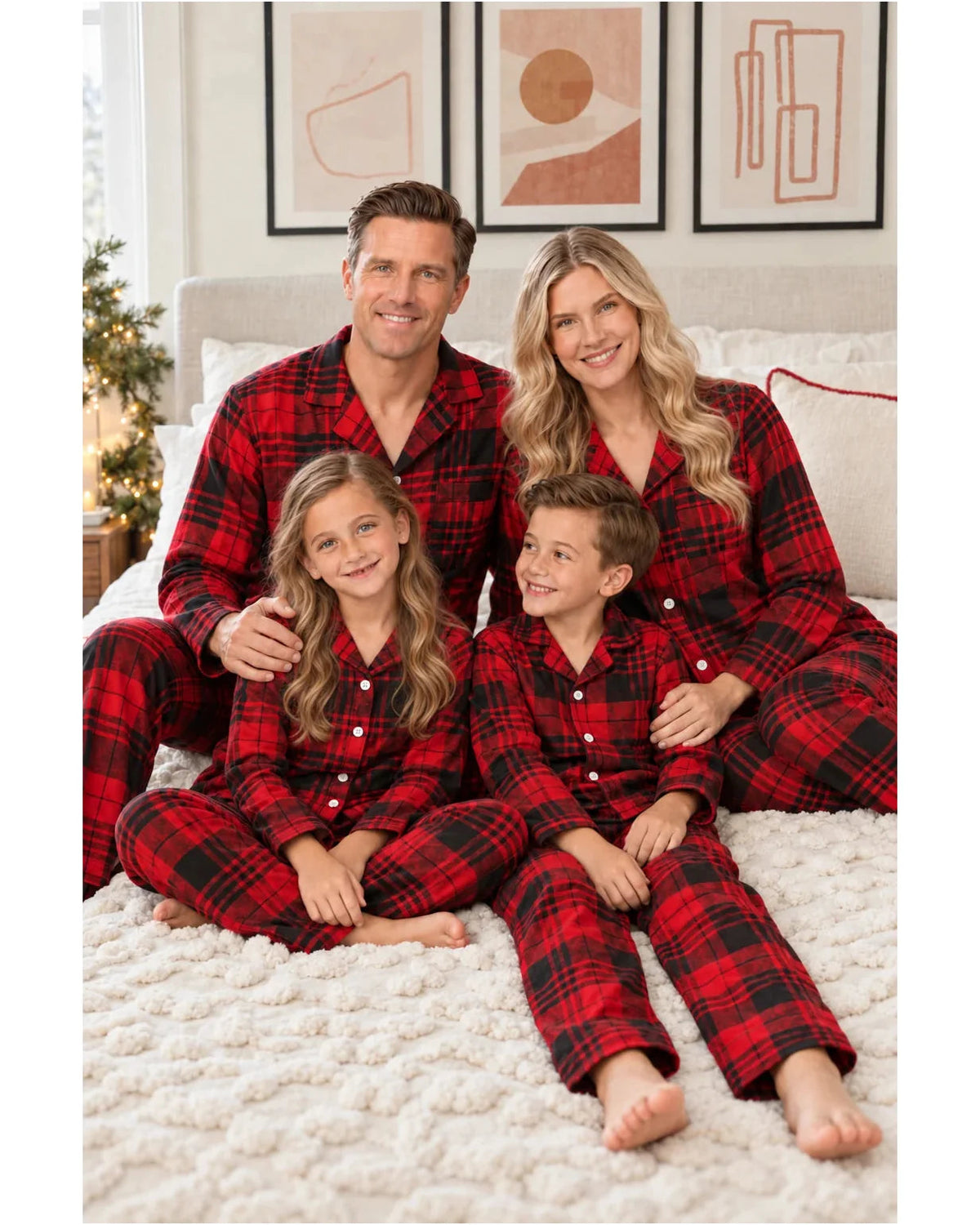 Family relaxing together on a cream blanket in matching red and black tartan pajamas.