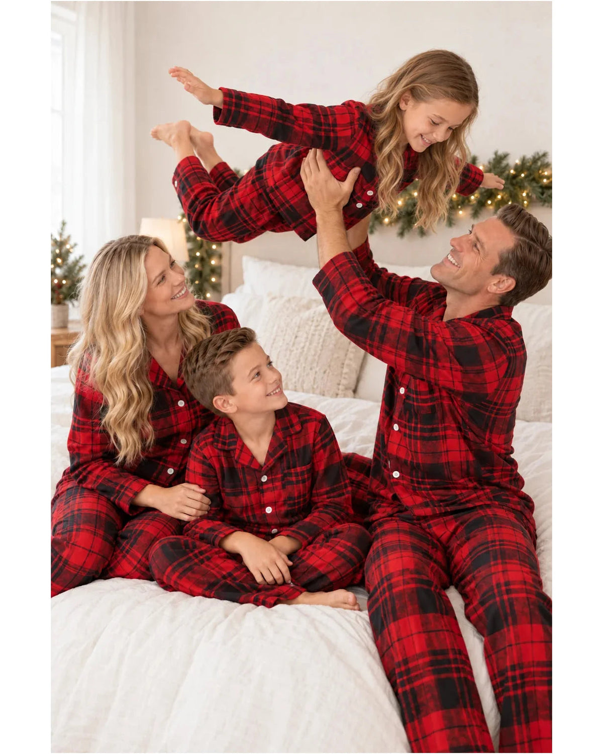 Father lifting his daughter as the family wears matching red and black tartan pajamas on a bed.