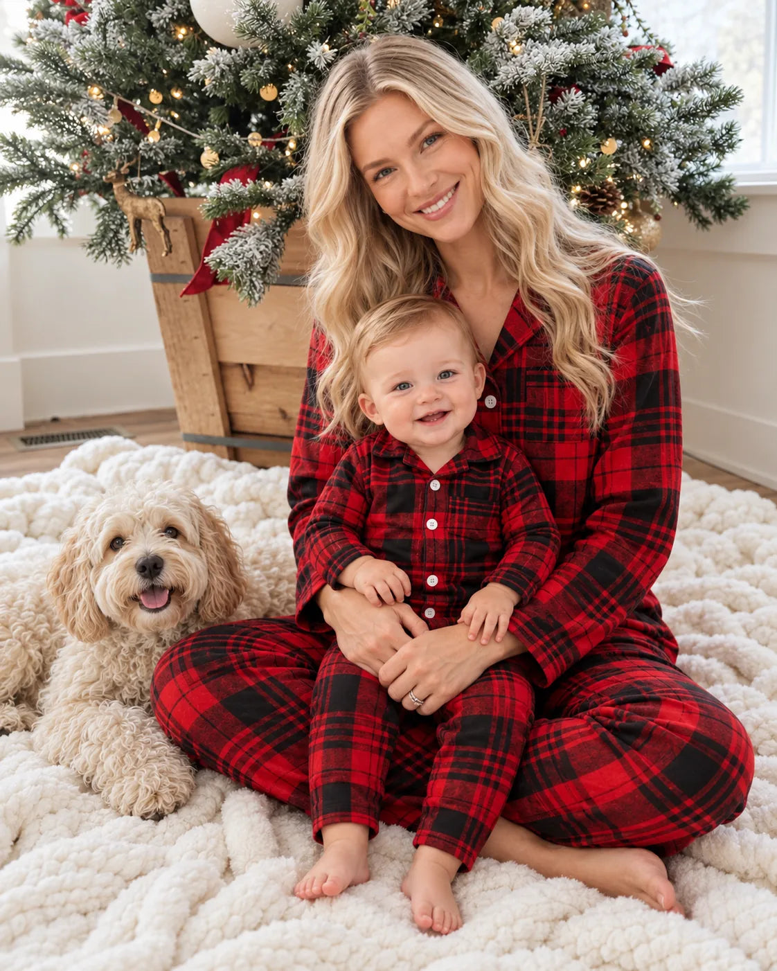 Mother and baby in red and black tartan pajamas beside a Christmas tree and cream-colored dog.