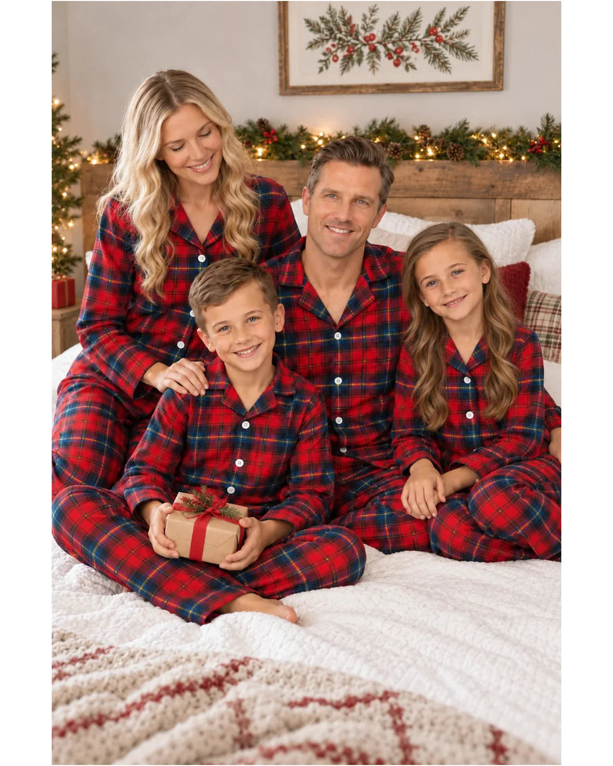 Family wearing red and blue plaid pajamas on a bed, with a boy holding a wrapped gift.
