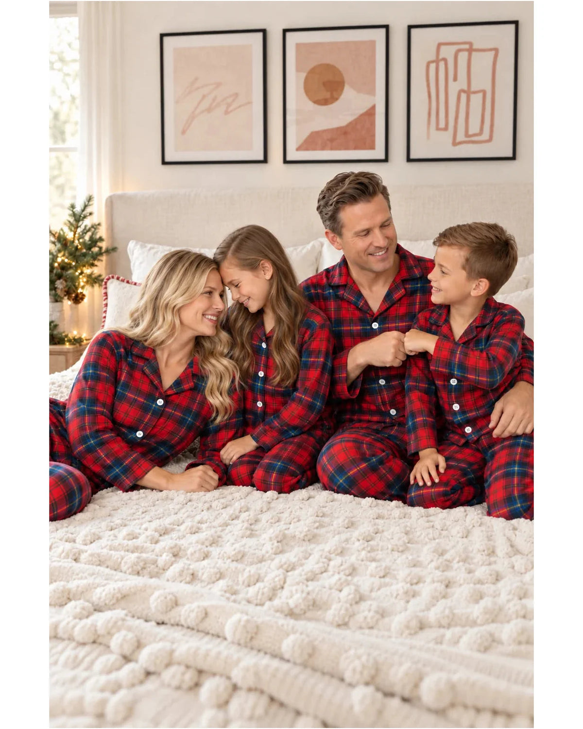 Family in red and blue plaid pajamas relaxing together on a white bed.