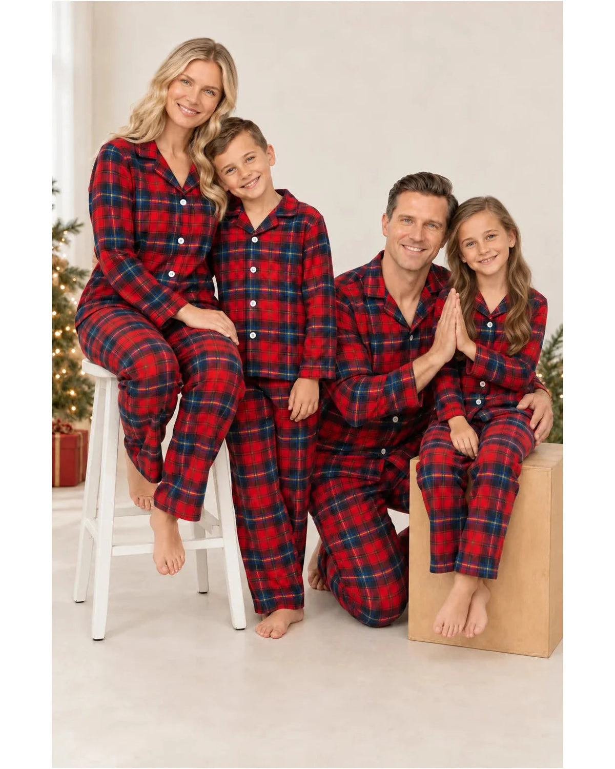Parents and children model matching red and blue plaid pajamas beside a stool and wooden cube.
