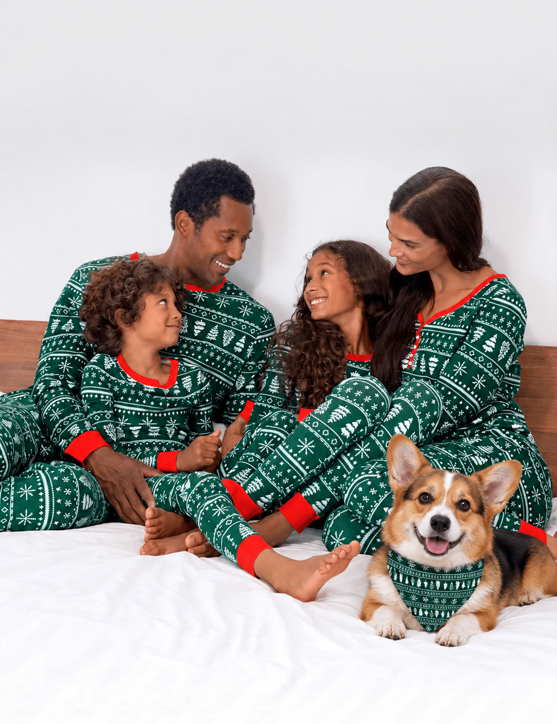 Family wearing matching Christmas pajamas with a Pembroke Welsh Corgi wearing the coordinating triangular dog bandana.