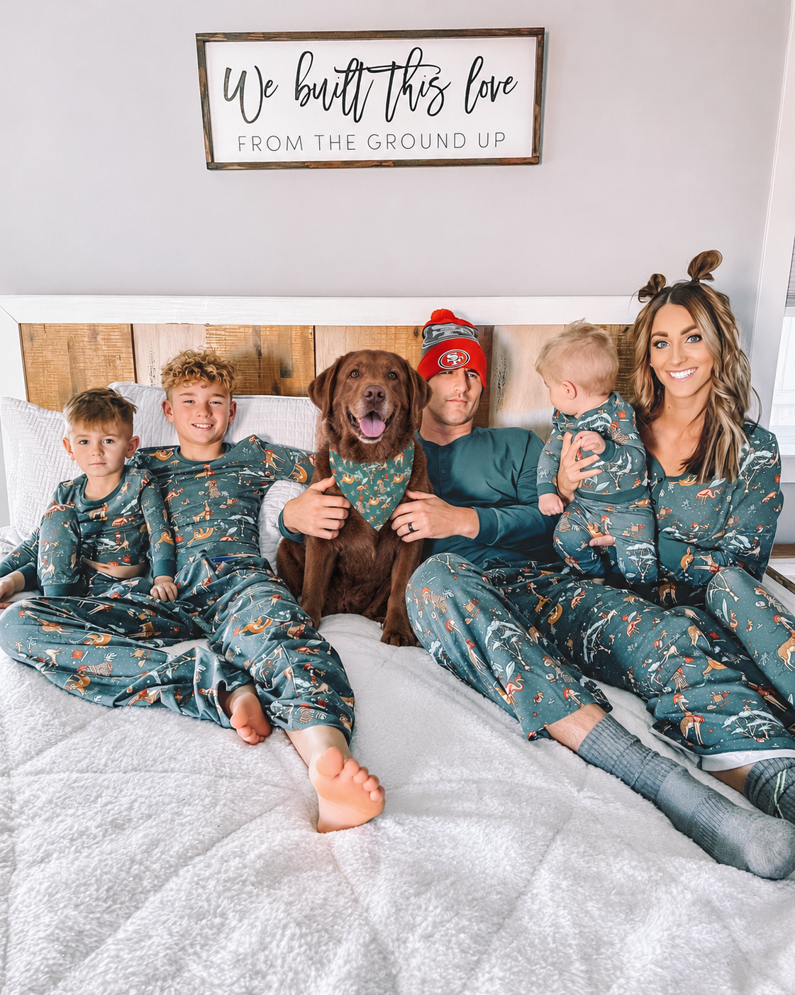 Family wearing matching Christmas pajamas with a Labrador Retriever wearing the coordinating triangular dog bandana.