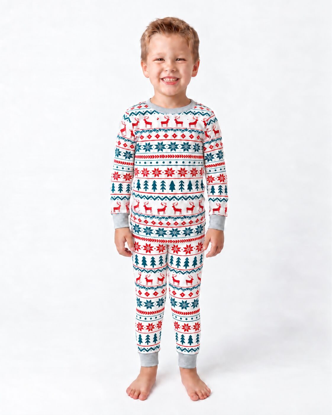 Bambino in pigiama natalizio bianco con renne rosse e motivi Fair Isle verdi, in piedi su sfondo bianco.