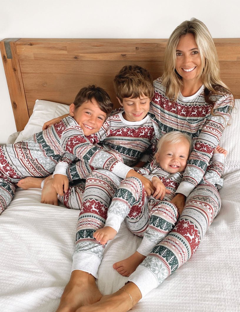 Mom Sitting Against Wooden Headboard with Three Boys in Matching Fair Isle Christmas Pajamas – All Four Smiling and Cuddling on White Bedding