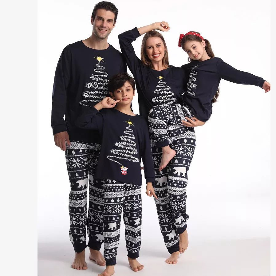 Familia posando con los brazos levantados con camisetas de pijama azul marino con árboles de Navidad y pantalones azul marino y blancos con estampado de osos polares sobre fondo blanco.