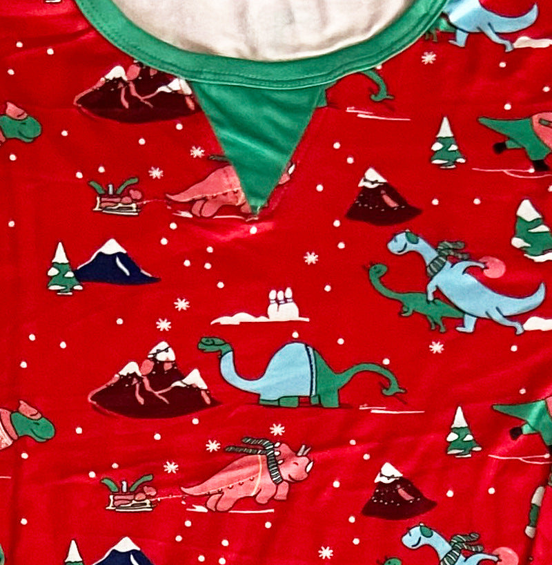 Close-up of a red dinosaur print Christmas pajama top showing the green crew neck and triangular neckline inset.